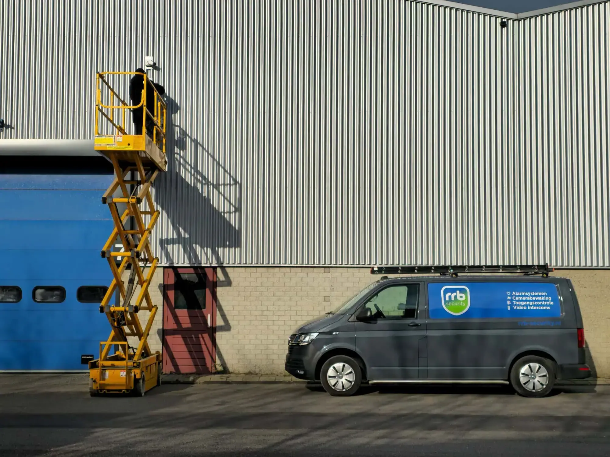 Technicus werkt aan camerabeveiliging bij een bedrijfsgebouw